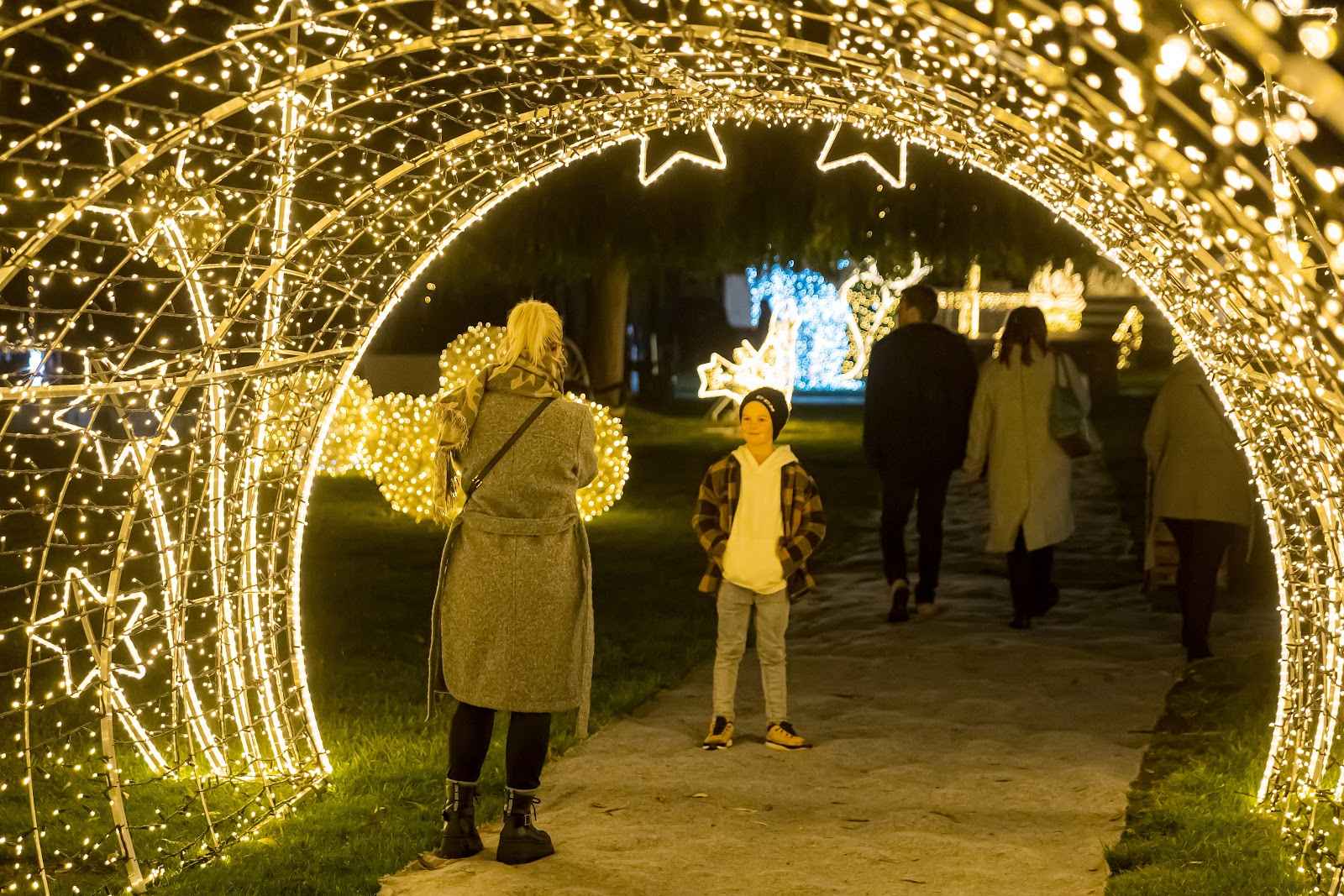 Visitors walking through a lit archway on the light trail at Žluté lázně in Prague.